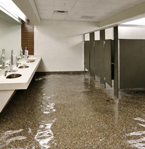 A large commercial public restroom with standing water covering the entire floor area