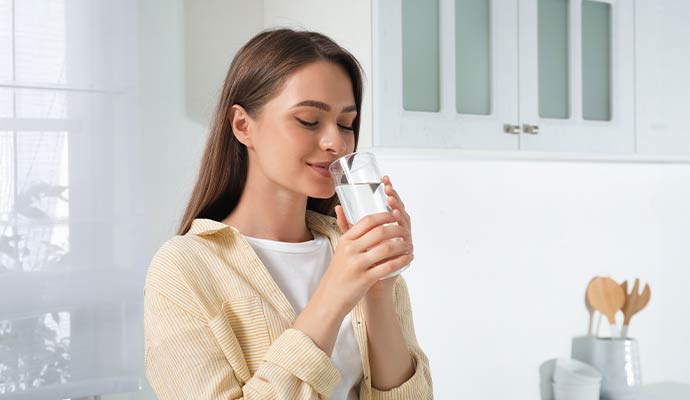 A woman drinking a glass of clear filtered water