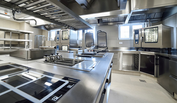 Commercial kitchen with stainless steel cooking equipment after grease cleaning