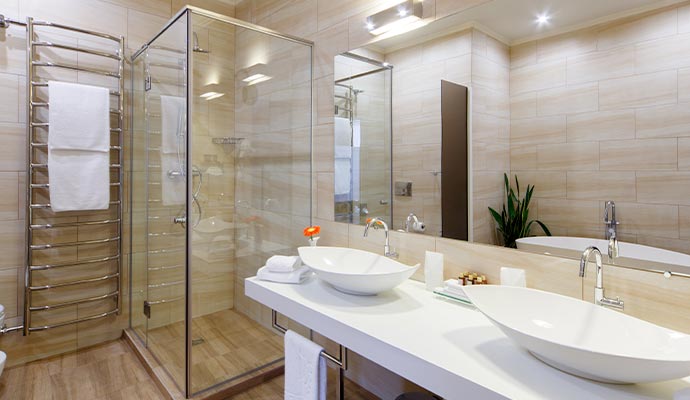 A modern hotel bathroom with a glass shower and double sinks