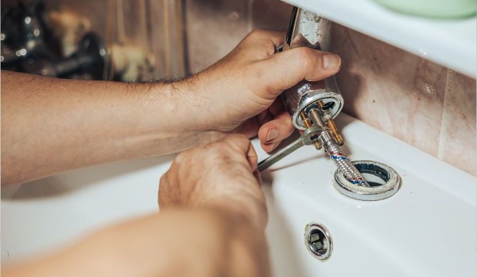Person repairing faucet with equipment
