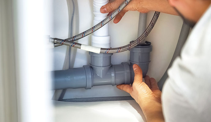 Plumber installing pipes under a sink