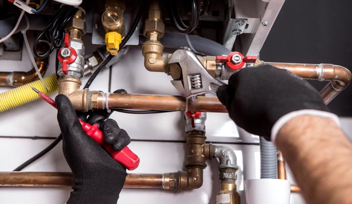 Professional plumber replacing boiler pipes