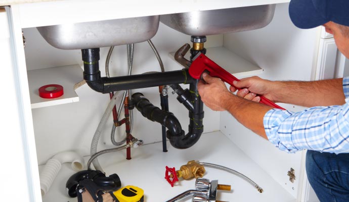 Plumber working on the pipes under a sink Plumber working on the pipes under a sink
