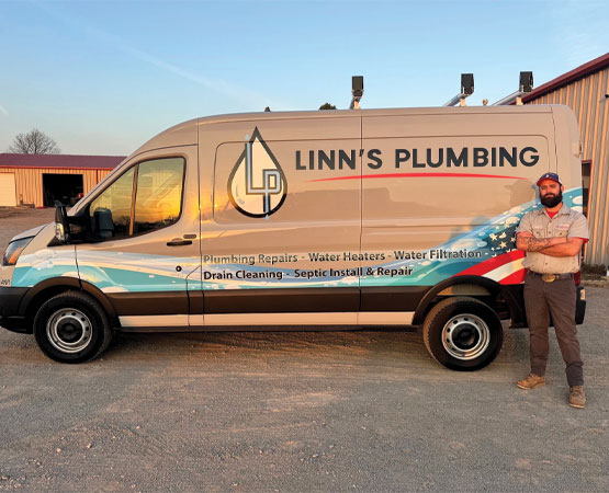 Plumber standing next to a Linn's Plumbing service van
