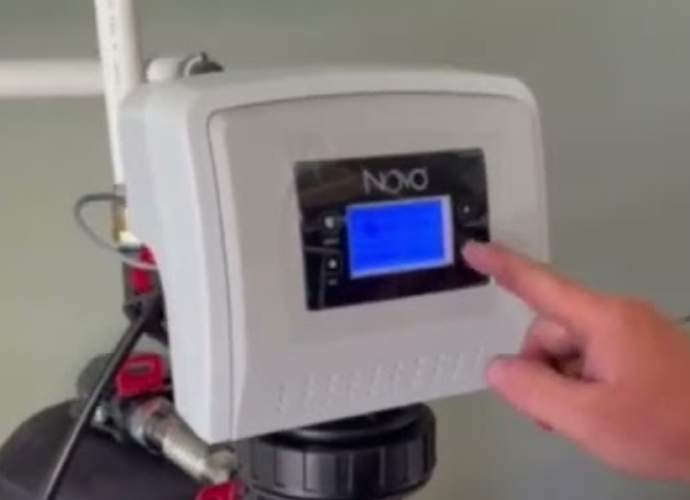 Happy plumber installing a Novo Water Softener with tools and pipes in Lincoln County.
