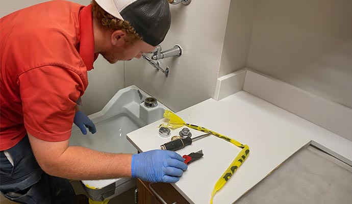 Plumber working on sink with utility knife