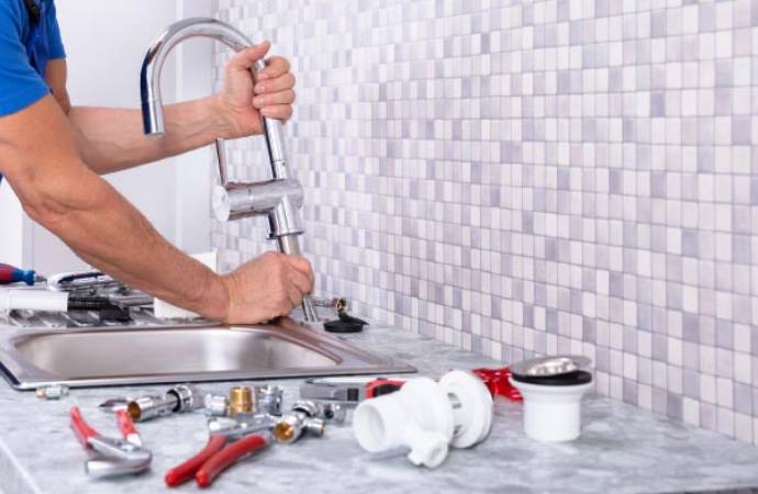Plumber installing new faucet on kitchen sink