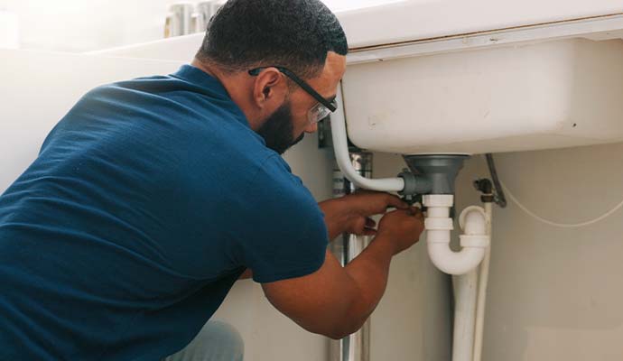 Professional plumber working under a kitchen sink