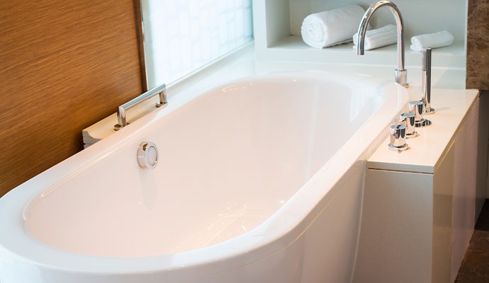 White acrylic deep soaking tub with deck faucet
