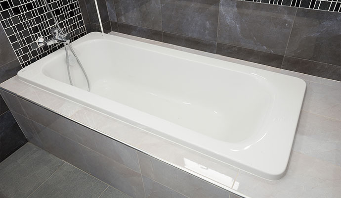 White drop-in bathtub in tiled deck surround