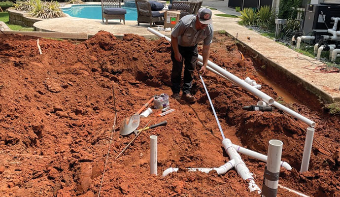 Plumber measuring pipes for an outdoor plumbing installation