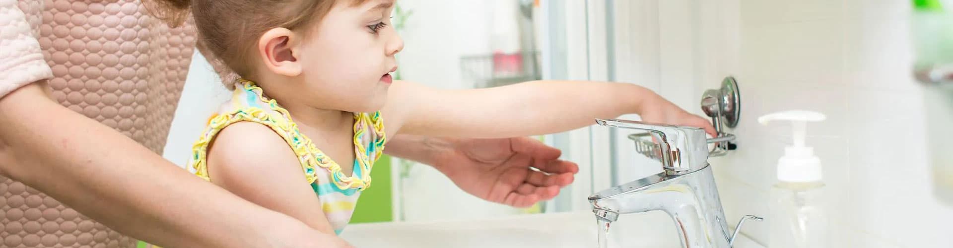 Little girl pouring water from the faucet
